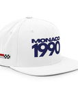 White cap with 'MONACO 1990' text and racing flag on a white background