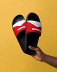 The Red's pool slides, red and white strap on black sole, held against yellow