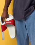 The Red's pool slides, red and white strap on white sole, held by model